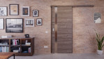 Front-Milieuansicht der vor der Wand laufenden HÖRMANN Schiebetür Pure 1 Gebürstete Lärche dunkel quer Duradecor DesignLine mit Lichtausschnitt Schlossseite