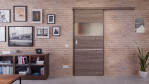 Front-Milieuansicht der vor der Wand laufenden HÖRMANN Schiebetür Pure 2 Gebürstete Lärche dunkel quer Duradecor DesignLine mit Lichtausschnitt quer mit Lisene Steel 79