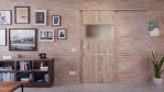 Front-Milieuansicht der vor der Wand laufenden HÖRMANN Schiebetür Pure 2 Nordeiche Duradecor DesignLine mit Lichtausschnitt quer mit Lisene Steel 79