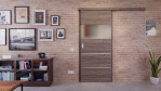 Front-Milieuansicht der vor der Wand laufenden HÖRMANN Schiebetür Pure 2 Gebürstete Lärche dunkel quer Duradecor DesignLine mit Lichtausschnitt quer mit Lisene Steel 80