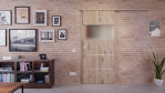 Front-Milieuansicht der vor der Wand laufenden HÖRMANN Schiebetür Pure 2 Nordeiche Duradecor DesignLine mit Lichtausschnitt quer mit Lisene Steel 80